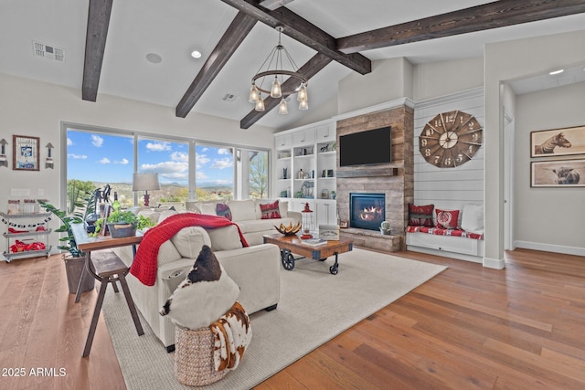 living area with visible vents, beamed ceiling, a fireplace, an inviting chandelier, and wood finished floors