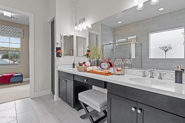 full bath featuring a sink, a shower stall, tile patterned flooring, double vanity, and baseboards