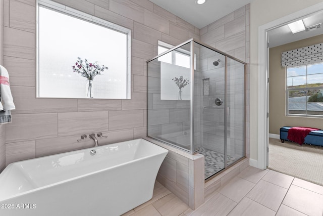 ensuite bathroom with a shower stall, a soaking tub, tile walls, and visible vents