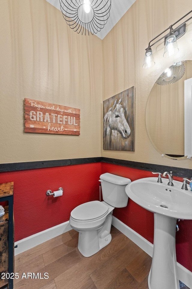 bathroom with a sink, toilet, baseboards, and wood finished floors