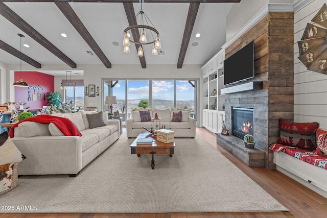 living room with a stone fireplace, visible vents, an inviting chandelier, and wood finished floors