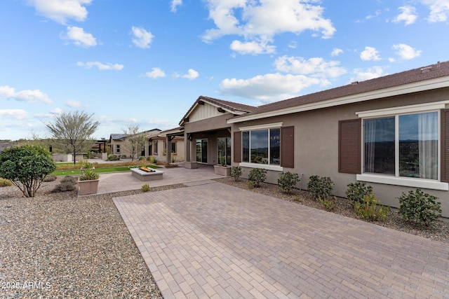 rear view of house with a patio and stucco siding