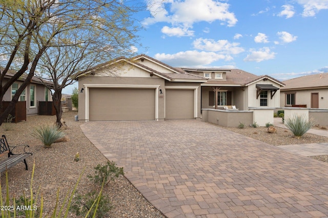 view of front facade featuring decorative driveway, a tile roof, an attached garage, and stucco siding