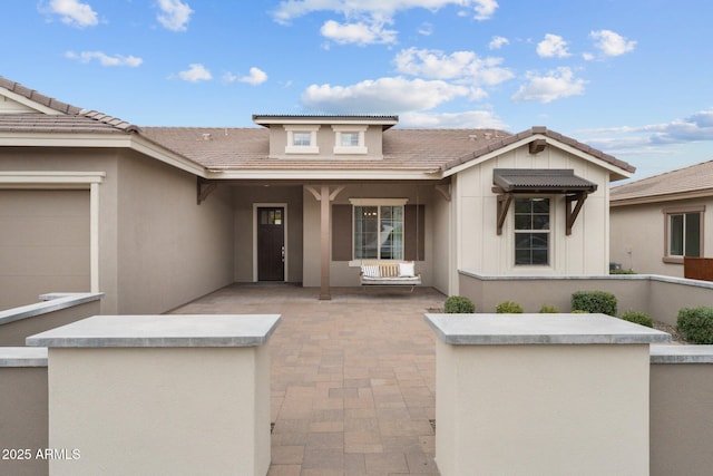 view of front of house with a tiled roof, stucco siding, and an attached garage