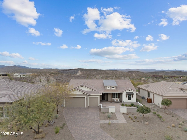 view of front of property featuring a tiled roof, stucco siding, decorative driveway, a garage, and a mountain view