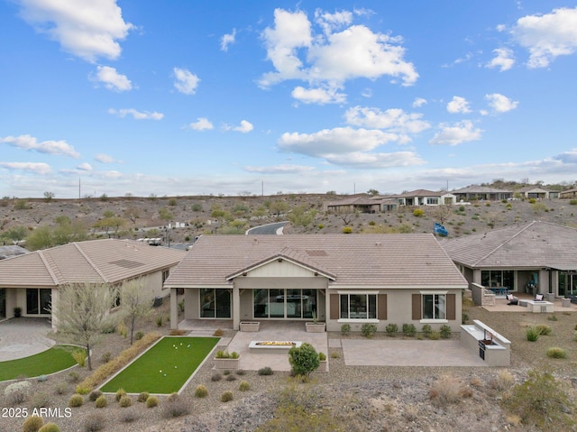 rear view of property featuring a tiled roof, an outdoor kitchen, stucco siding, and a patio area