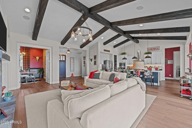 living area featuring baseboards, high vaulted ceiling, light wood-style flooring, beamed ceiling, and a notable chandelier