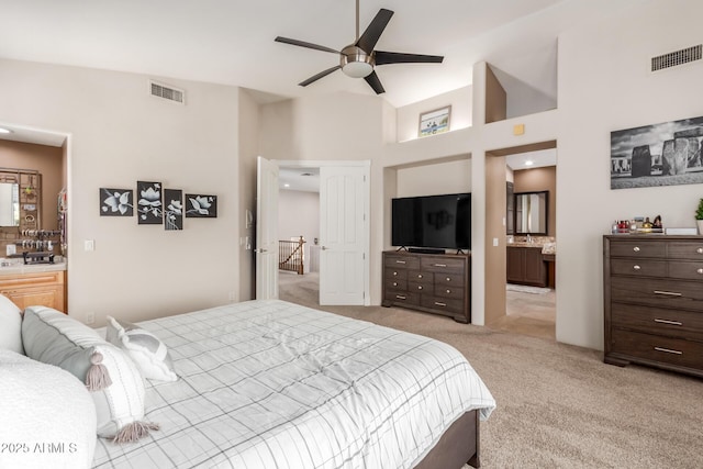 bedroom featuring visible vents, light colored carpet, ensuite bathroom, and ceiling fan