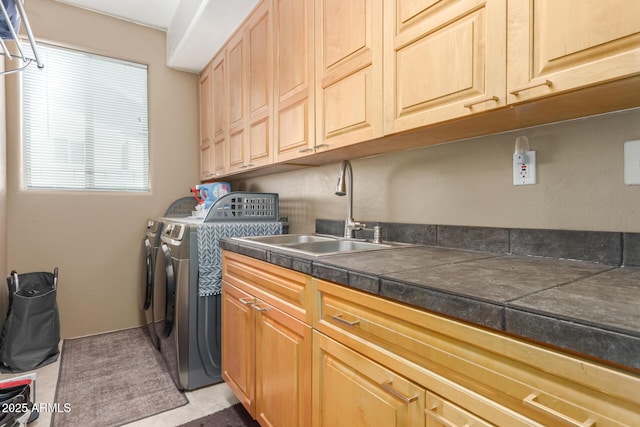 washroom with a sink, cabinet space, and washer and clothes dryer