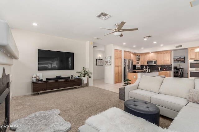 living area featuring light carpet, visible vents, and a ceiling fan