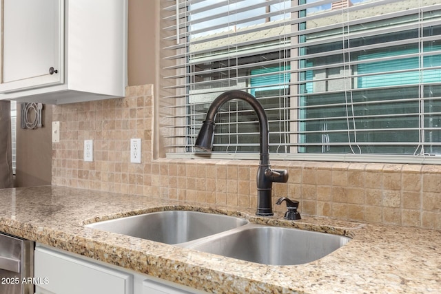 room details featuring white cabinets, tasteful backsplash, and sink