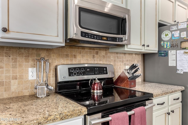 kitchen with light stone countertops, white cabinets, appliances with stainless steel finishes, and tasteful backsplash