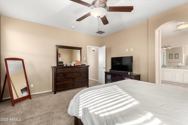 bedroom featuring ceiling fan, ensuite bath, and light carpet