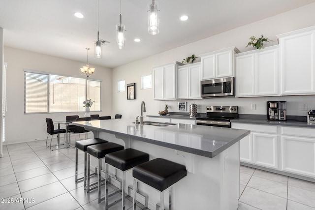 20496 W Valley View Dr, Buckeye, AZ 85396 - kitchen featuring appliances with stainless steel finishes, a sink, light tile patterned flooring, a kitchen island with sink, and white cabinetry