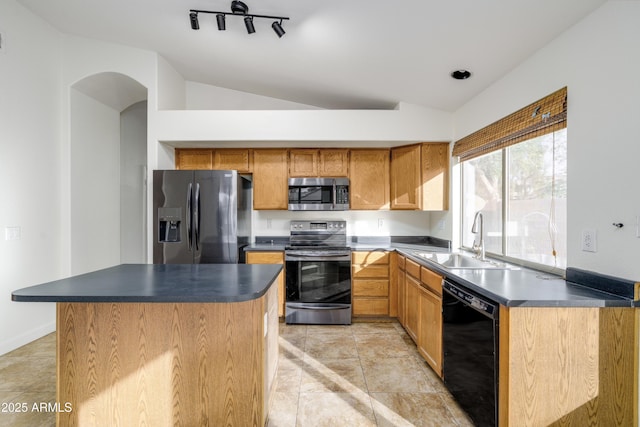 kitchen with dark countertops, a sink, appliances with stainless steel finishes, and vaulted ceiling