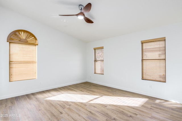 empty room with wood finished floors, a ceiling fan, baseboards, and vaulted ceiling