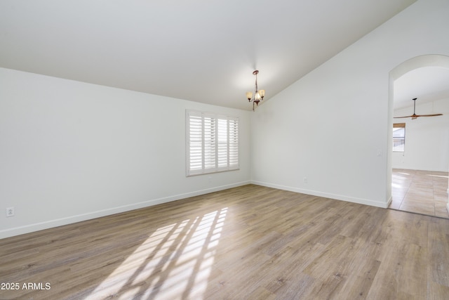 empty room with plenty of natural light, baseboards, light wood-type flooring, and lofted ceiling