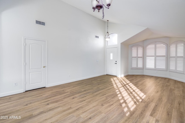 unfurnished living room with visible vents, baseboards, a notable chandelier, and light wood finished floors