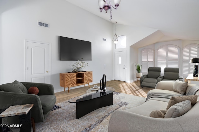 living room featuring light wood-type flooring, visible vents, baseboards, and high vaulted ceiling