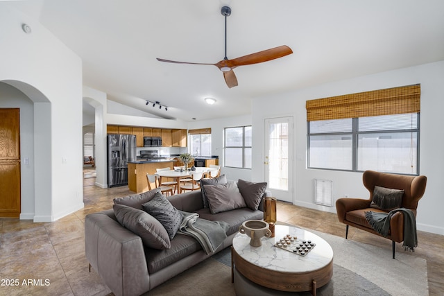 living area with light tile patterned floors, baseboards, lofted ceiling, arched walkways, and ceiling fan