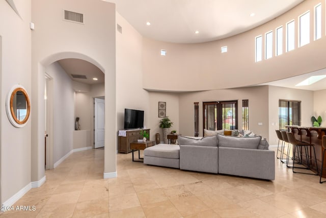 tiled living room with a towering ceiling and a wealth of natural light