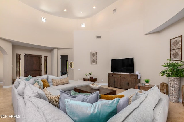 living room with a towering ceiling and light tile patterned flooring