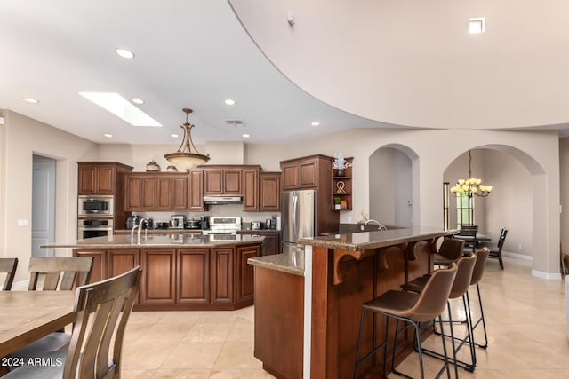 kitchen featuring pendant lighting, a breakfast bar area, stainless steel appliances, and a center island with sink