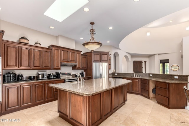 kitchen featuring sink, a kitchen island with sink, dark stone countertops, stainless steel appliances, and decorative light fixtures