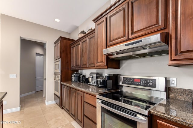 kitchen with appliances with stainless steel finishes, light tile patterned floors, and dark stone counters