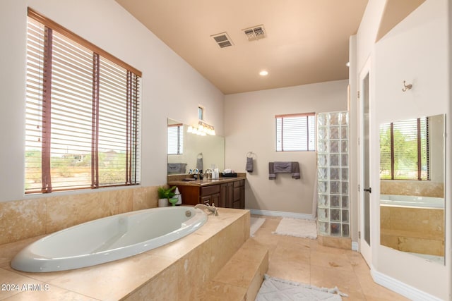 bathroom with vanity, tile patterned flooring, and tiled bath