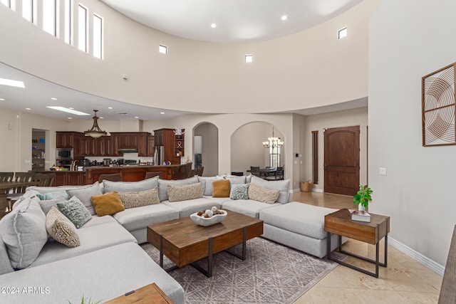 living room featuring a towering ceiling, light tile patterned floors, and a notable chandelier