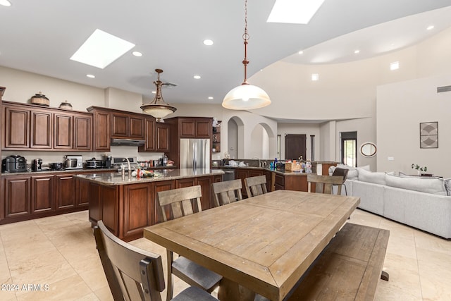 dining space with light tile patterned flooring, a skylight, and sink