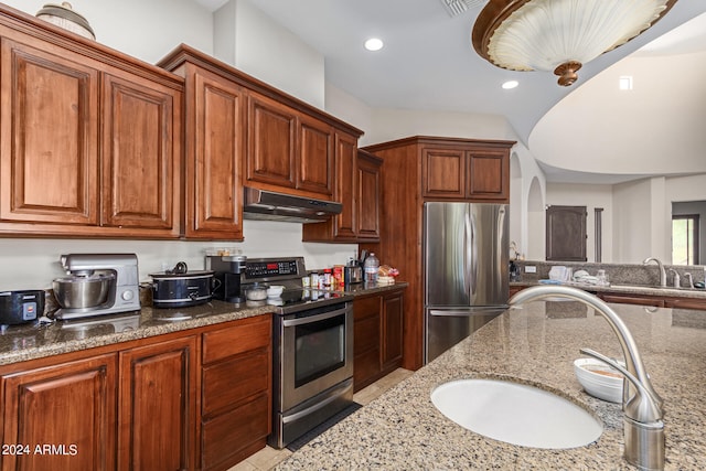 kitchen with light stone counters, stainless steel appliances, and sink