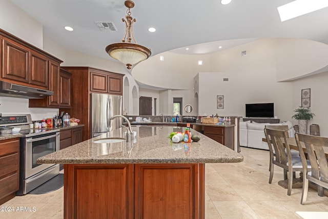 kitchen with light stone countertops, an island with sink, appliances with stainless steel finishes, and sink