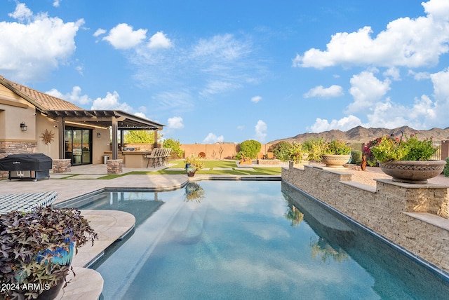 view of pool featuring a patio, a mountain view, and area for grilling