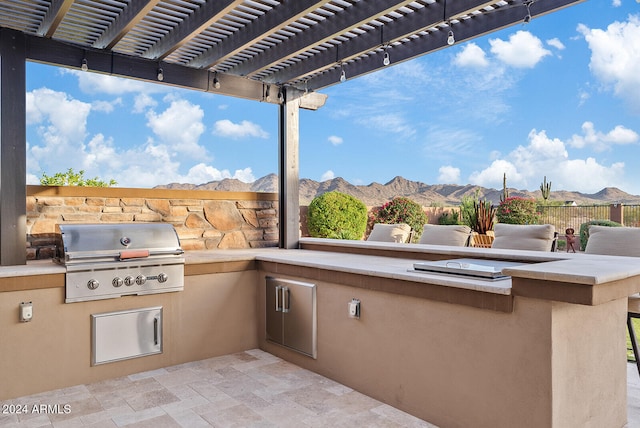 view of patio with a mountain view, grilling area, an outdoor kitchen, and a pergola