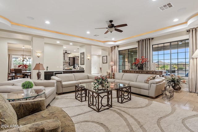 living room featuring ceiling fan with notable chandelier and a raised ceiling