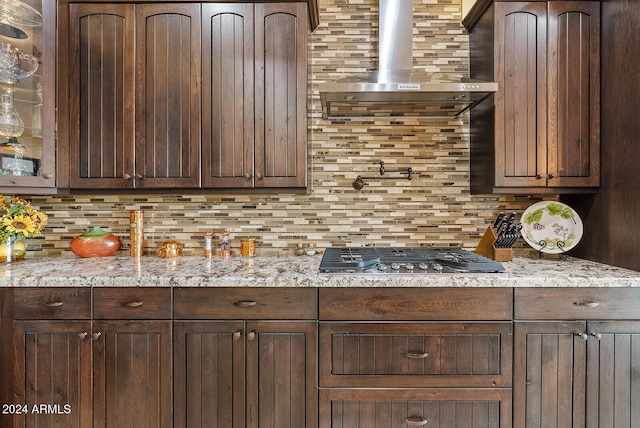 kitchen featuring stainless steel gas stovetop, light stone countertops, and dark brown cabinets