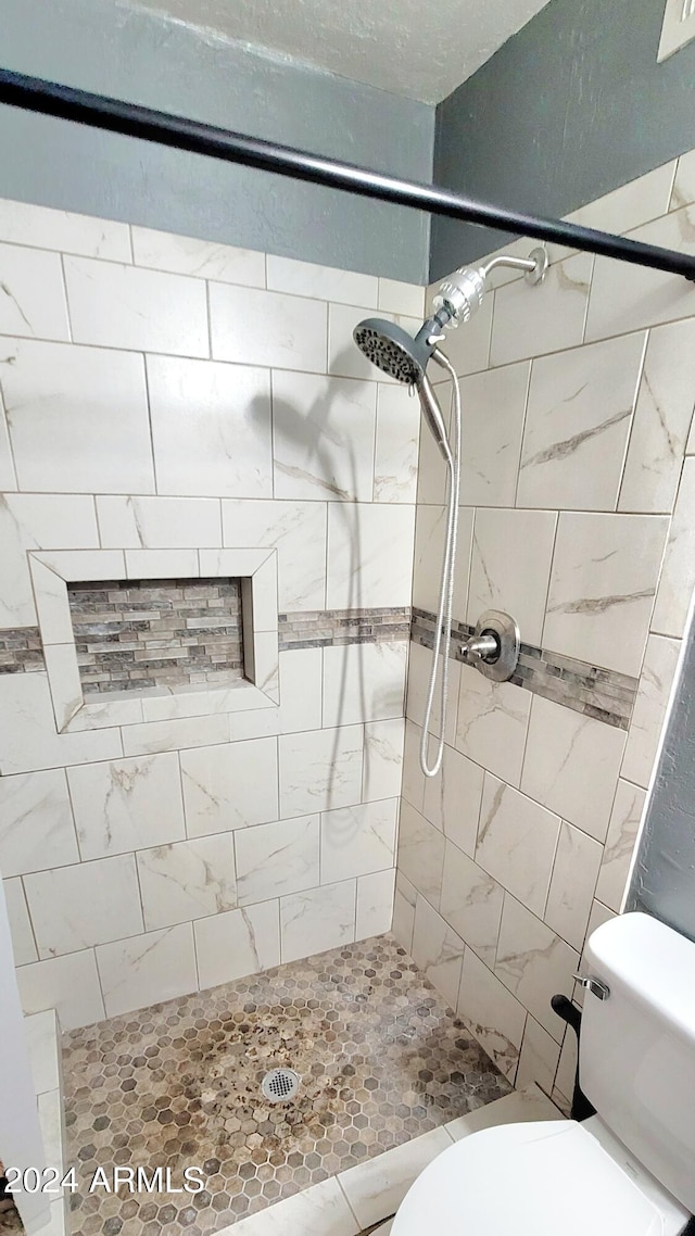 bathroom with toilet and tiled shower