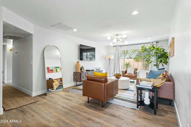 living room with light hardwood / wood-style floors and an inviting chandelier