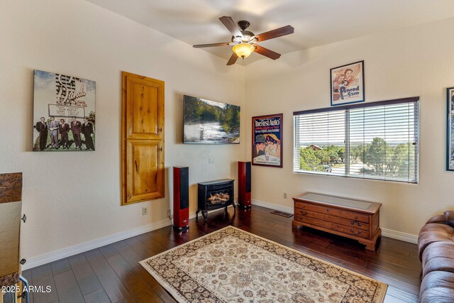 2335 Voyager Cir, Overgaard, AZ 85933 - living area featuring a wood stove, ceiling fan, dark wood finished floors, and baseboards
