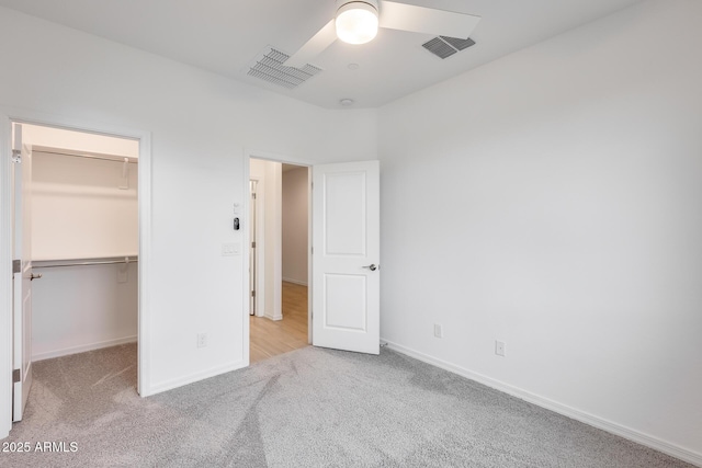 unfurnished bedroom featuring visible vents, a spacious closet, and carpet flooring