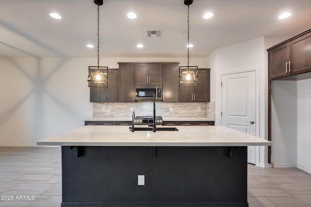 kitchen with a sink, stainless steel microwave, visible vents, and decorative backsplash