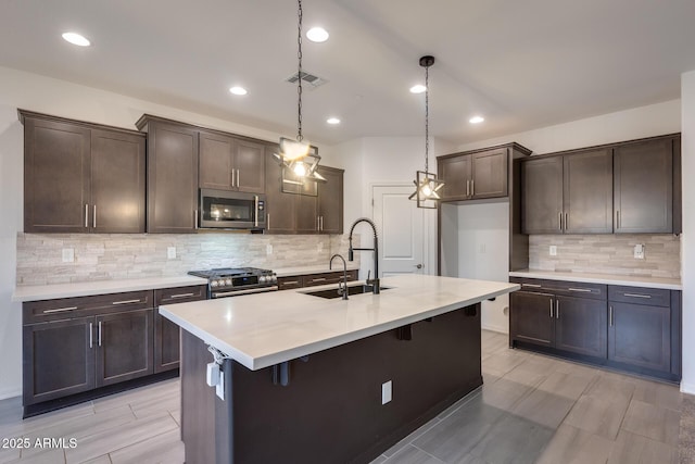 kitchen with visible vents, dark brown cabinets, light countertops, stainless steel appliances, and a sink