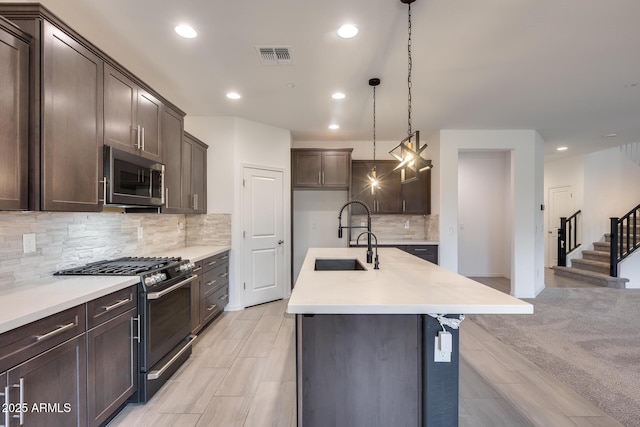 kitchen featuring visible vents, a sink, stainless steel appliances, dark brown cabinetry, and light countertops