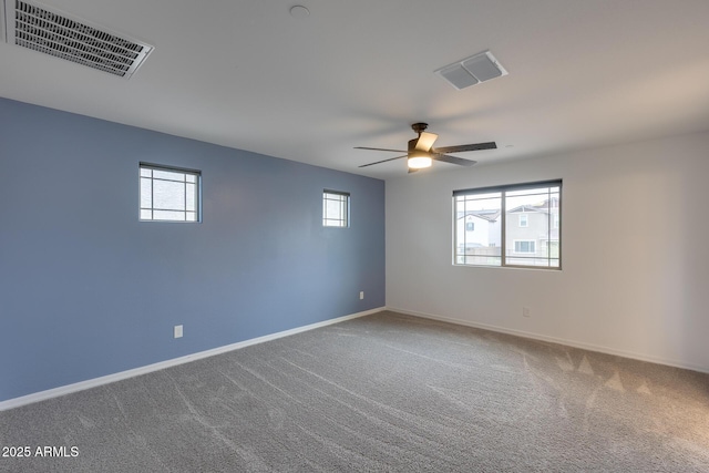 carpeted spare room featuring visible vents, a ceiling fan, and baseboards