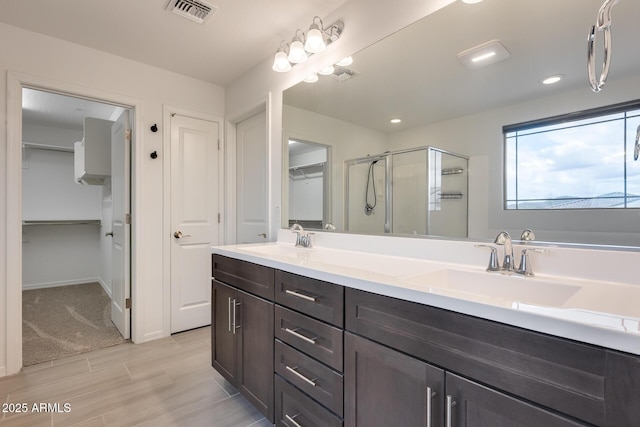 full bathroom with double vanity, visible vents, a stall shower, and a sink