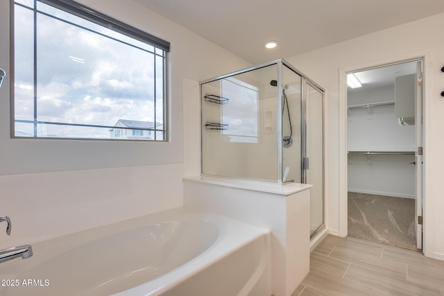 full bathroom featuring a spacious closet, a shower stall, baseboards, a garden tub, and recessed lighting