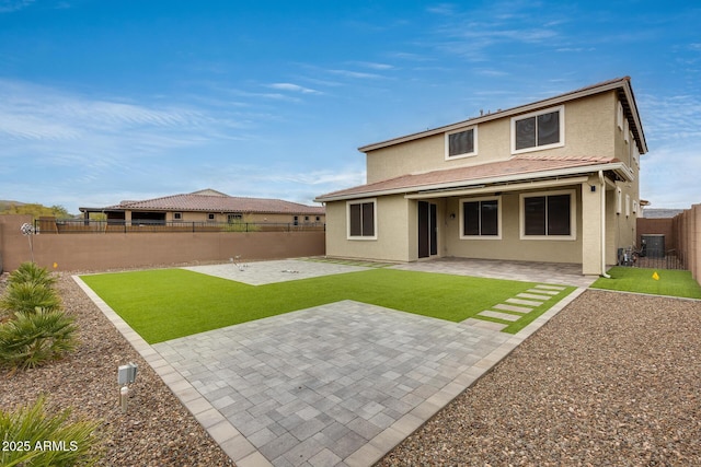 back of property with a patio area, stucco siding, a yard, and a fenced backyard