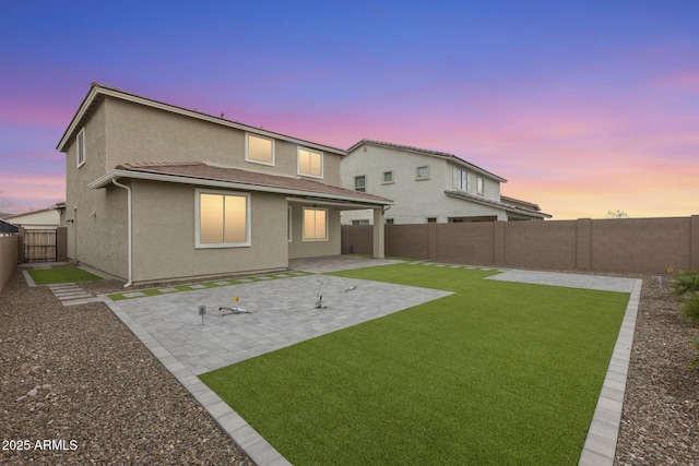 rear view of property featuring a fenced backyard, stucco siding, a tiled roof, a patio area, and a lawn